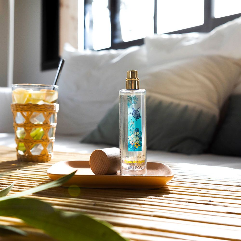 Flacon de parfum sur un plateau. Sur une table avec un verre de boisson et décoration. Bouchon en bois à côté.
