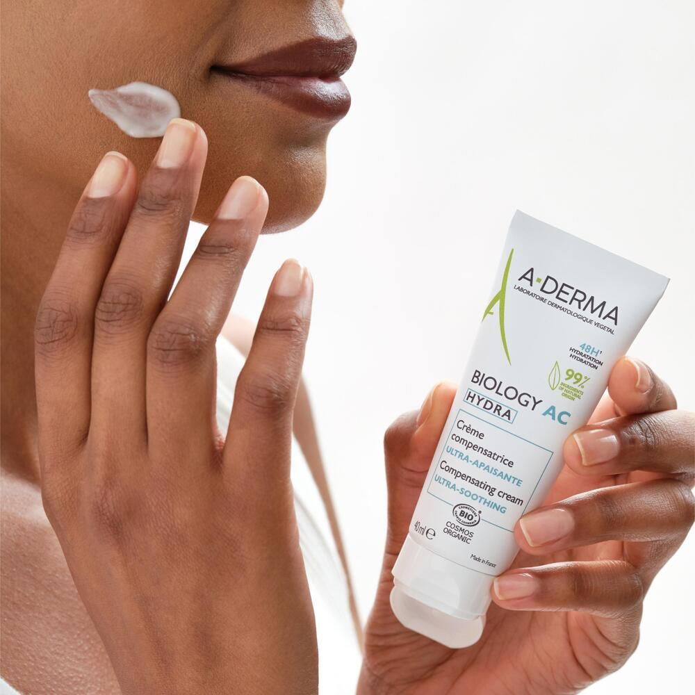 Personne appliquant la crème A-DERMA BIOLOGY AC HYDRA. Tube blanc, accents verts. 40ml. Inscription : Ultra-apaisante.