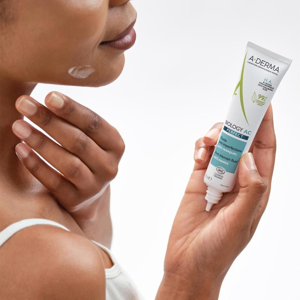 Personne tenant un tube A-DERMA BIOLOGY AC PERFECT. Application sur la peau.