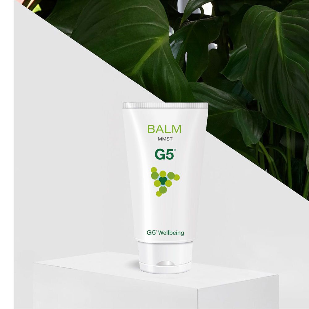 Weiße Tube mit grüner Schrift. Auf der Tube steht "BALM MMST G5". Die Tube steht auf einer weißen Plattform vor Grün.