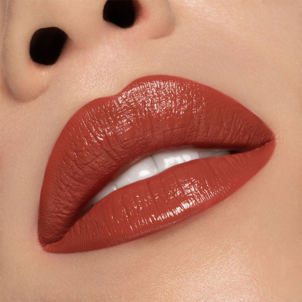 Nahaufnahme von Lippen, bedeckt mit semi-mattem, pfirsichfarbenem Lippenstift. Hautton sichtbar. Glänzendes Finish.