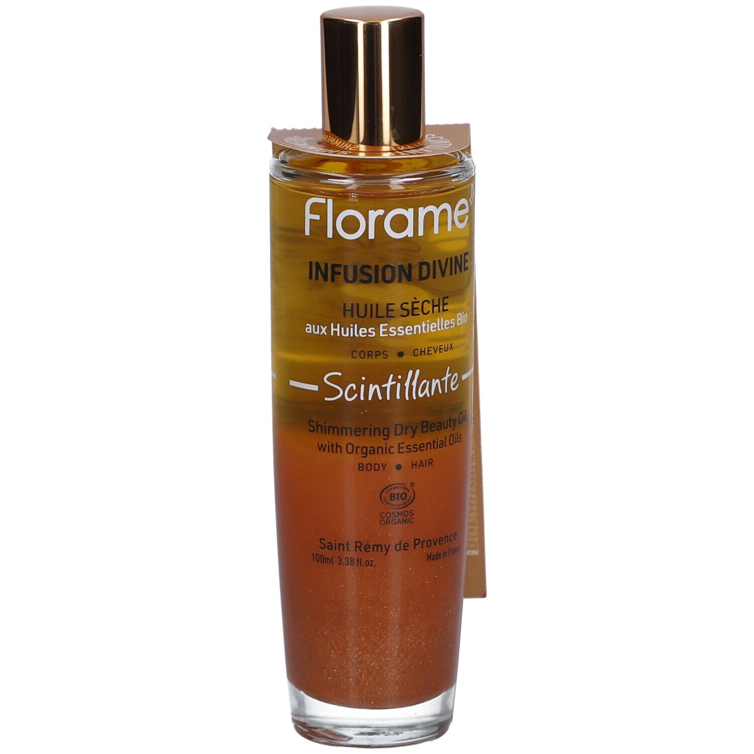 Flacon en verre avec bouchon doré. Étiquette avec nom et texte du produit. Liquide aux tons or et bronze.