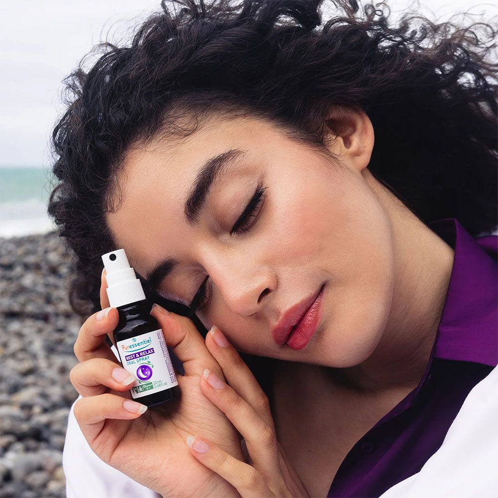 Femme tenant Puresentiel Sommeil Spray buccal. Flacon brun avec vaporisateur. Femme endormie.