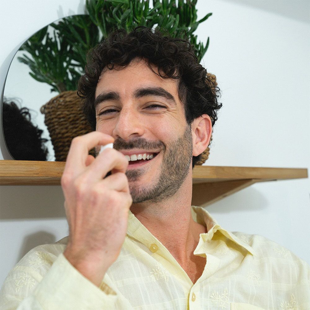 Homme vaporisant Puresentiel Sommeil Spray buccal. Flacon brun avec vaporisateur. Homme souriant.