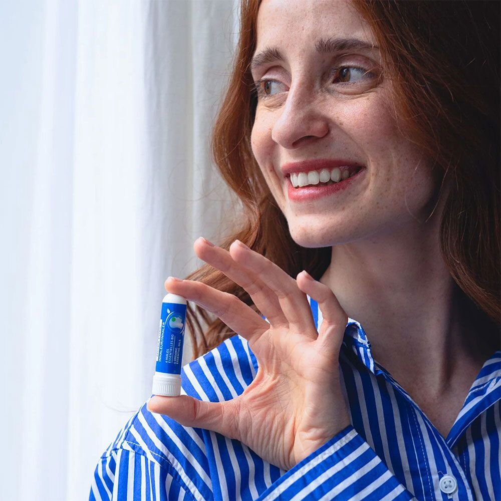 Frau mit Inhalator. Sie hält ihn in der Hand. Blau-weiß gestreiftes Hemd.
