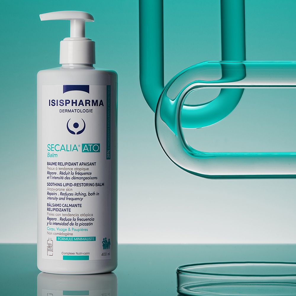 Weiße Flasche mit Pumpe. Aufschrift: ISISPHARMA, Secalia Ato Balm. Hintergrund mit blauen Rohren.