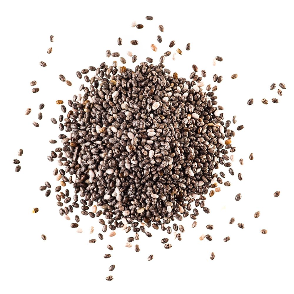 Tas de graines de chia sur fond blanc. Petites graines ovales, partiellement dispersées.