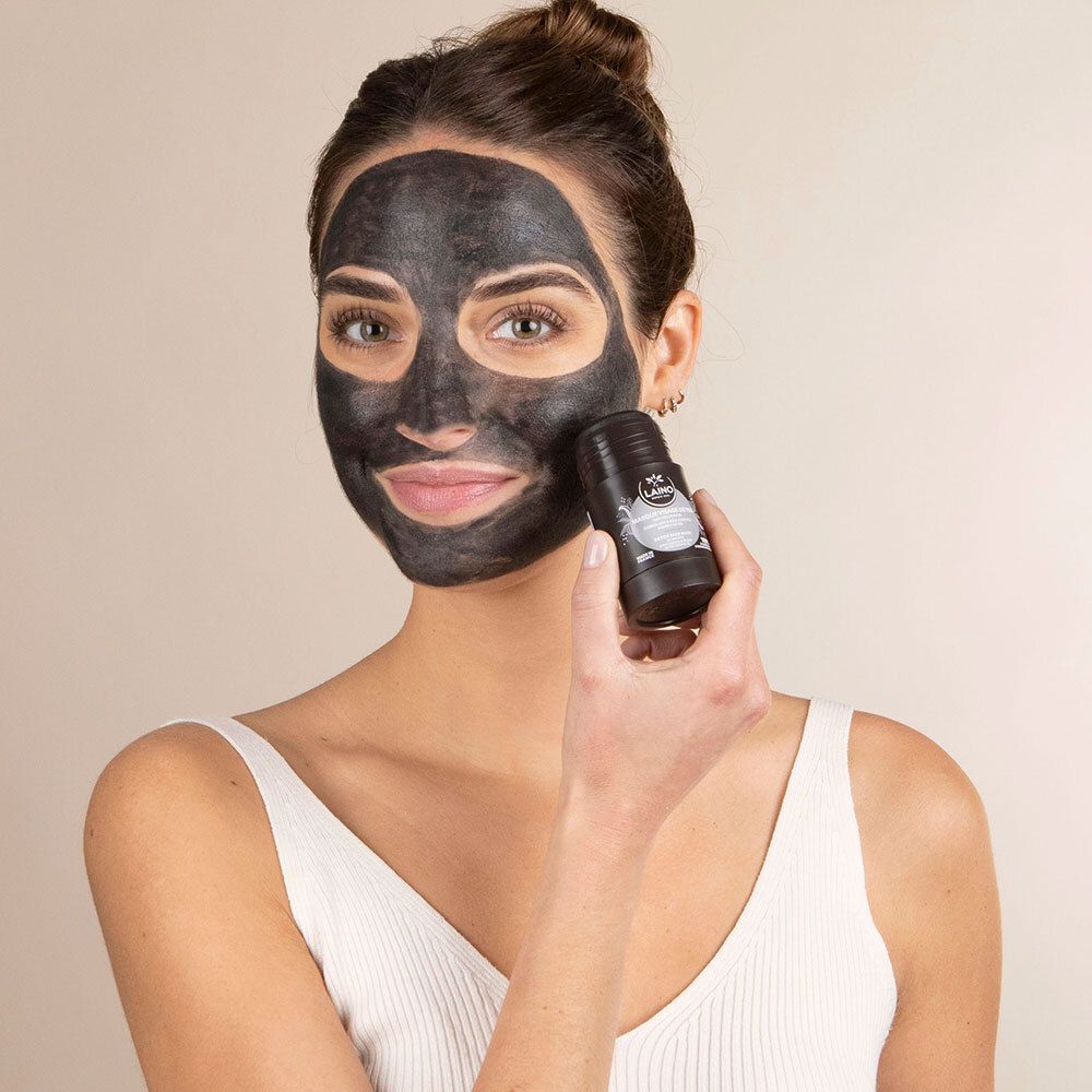 Frau mit schwarzer Gesichtsmaske. Sie hält eine schwarze zylindrische Verpackung in der Hand.