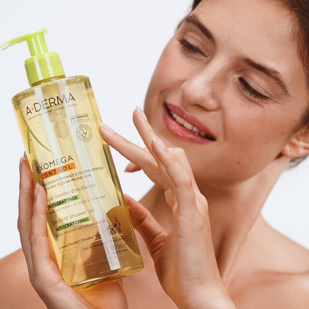 Femme tenant l'huile lavante A.DERMA Exomega Control. Produit et emballage visibles.