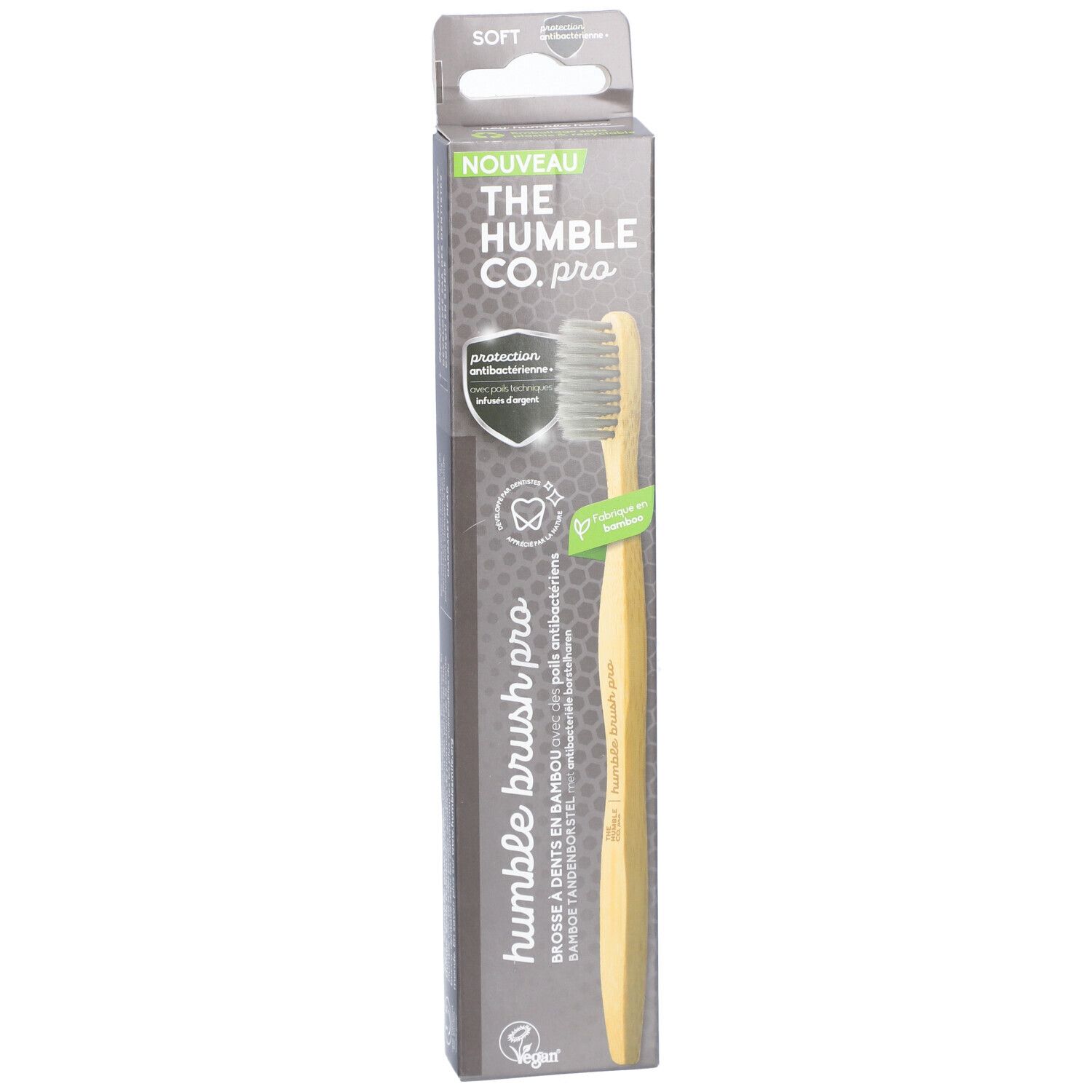 Brosse à dents dans son emballage. Manche en bambou, poils gris. Nom et logo du produit sur l'emballage.