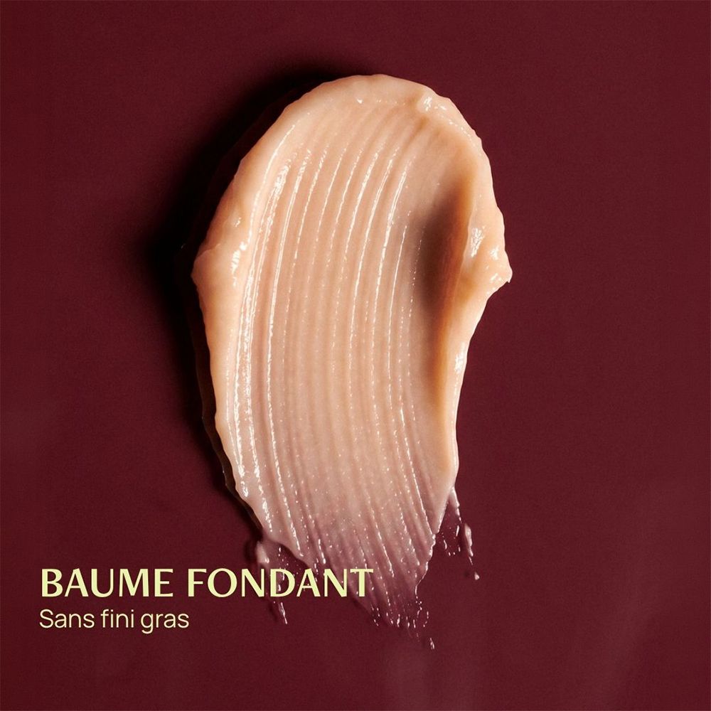 Eine cremige, hellbeige Textur mit Rillen, die auf einem dunkelroten Hintergrund liegt. "BAUME FONDANT Sans fini gras".