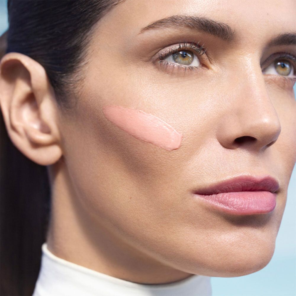 Visage de femme avec crème rose sur la joue. Produit de soin de la peau.