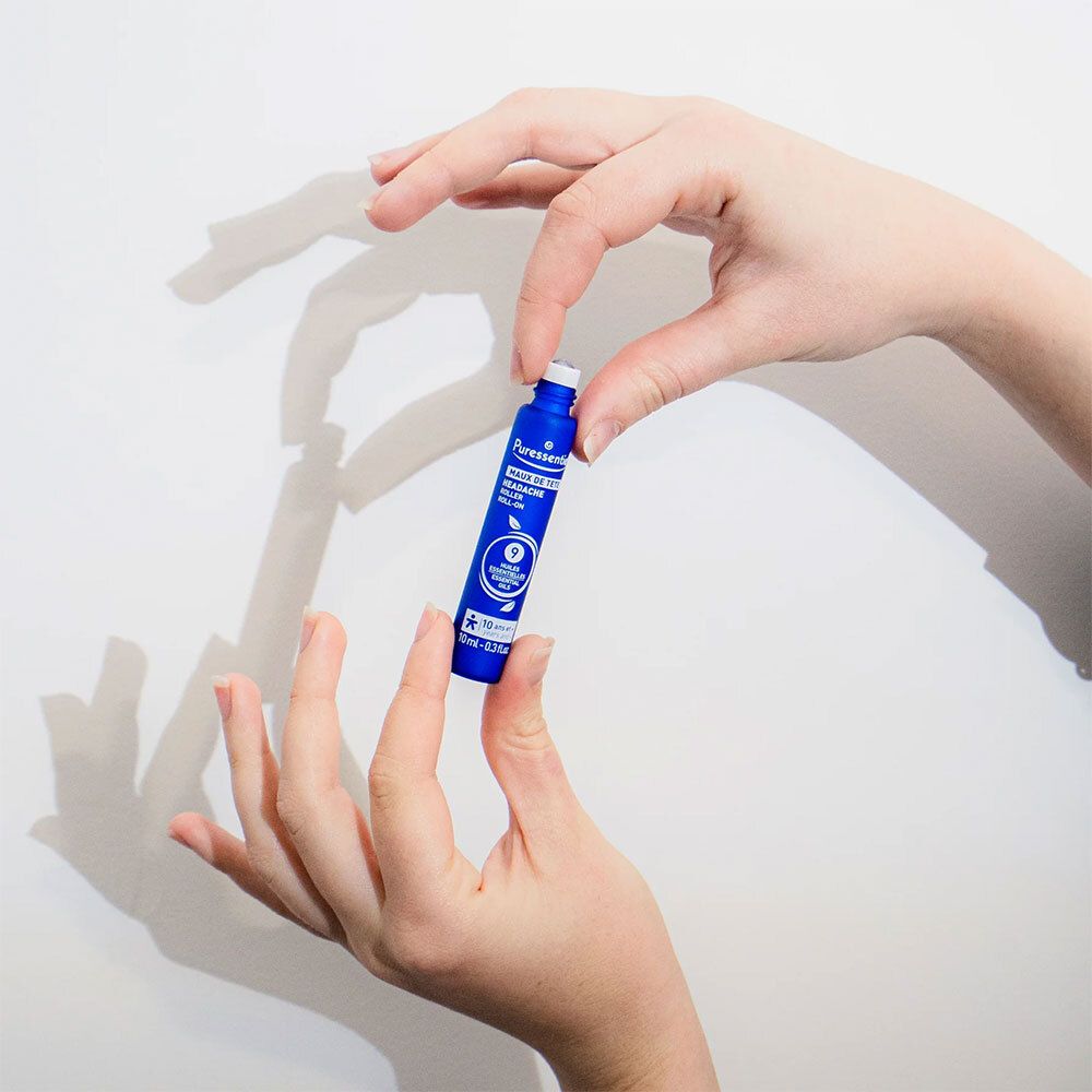 Personne tient roll-on bleu. Marque : Puressentiel. Texte : Maux de tête. Petit produit.