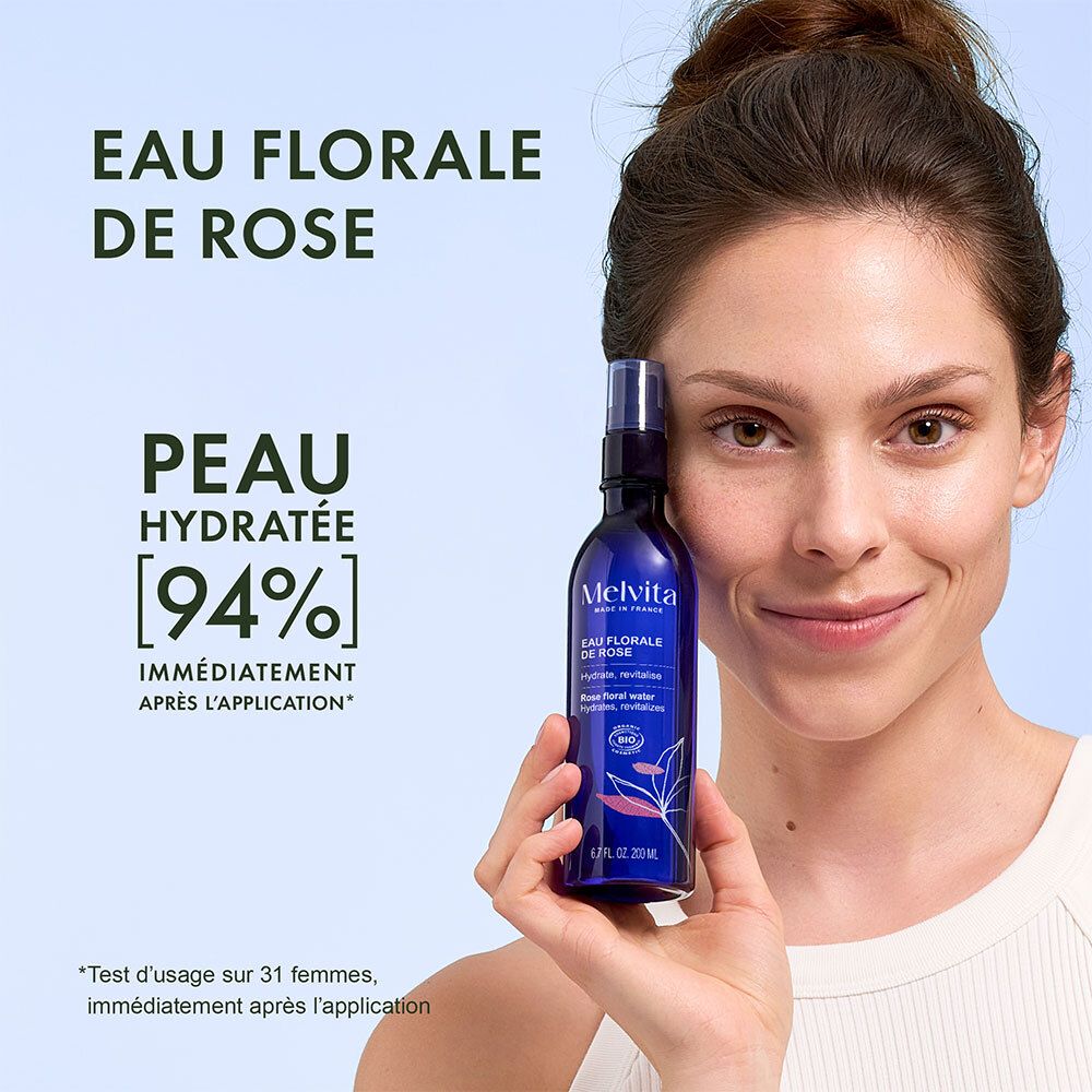 Frau hält Melvita Rosenblütenwasser Flasche, Haut wird mit 94% Feuchtigkeit versorgt.