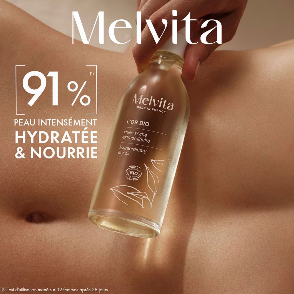 Melvita L'Or Bio Ölflasche. Hand hält Flasche über Haut. Text: 91% hydratisiert & genährt.