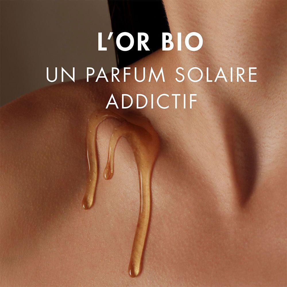 Goldfarbenes Öl tropft auf Haut. Text: L'Or Bio, ein süchtig machender Sonnen-Duft.
