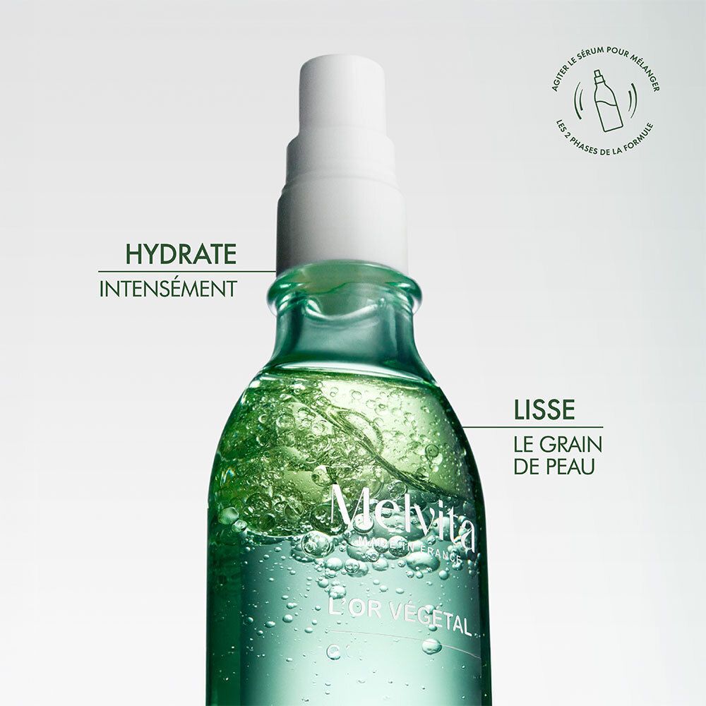 Nahaufnahme der Flasche. Melvita L'Or Végétal Serum. Text: Hydratisiert intensiv. Glättet die Haut.