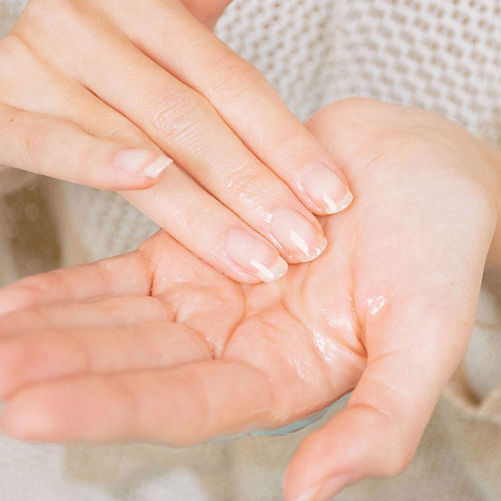 Hände mit Öl. Die Handflächen sind mit Öl bedeckt. Helle Haut, kurze Fingernägel. Nahaufnahme.