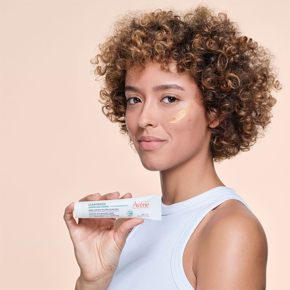 Femme tenant un tube. Crème sur la peau. Tube blanc avec nom du produit et marque.