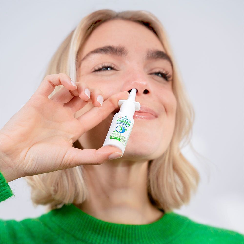 Femme tenant un spray nasal. Inscription : Puressentiel Respiratoire Sinus Express Spray Nasal. La femme porte un pull vert.