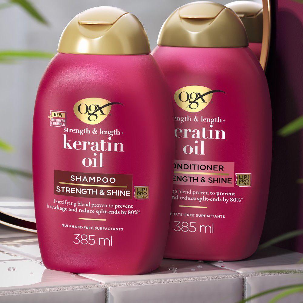 Zwei rote Shampoo-Flaschen mit goldfarbenen Deckeln. Text: OGX, Keratin Oil, Shampoo, 385 ml.