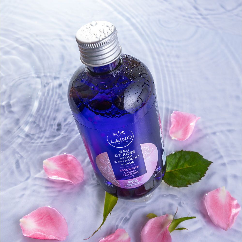 Eine Flasche LAINO Eau de Rose in Wasser mit Rosenblättern und einem grünen Blatt.