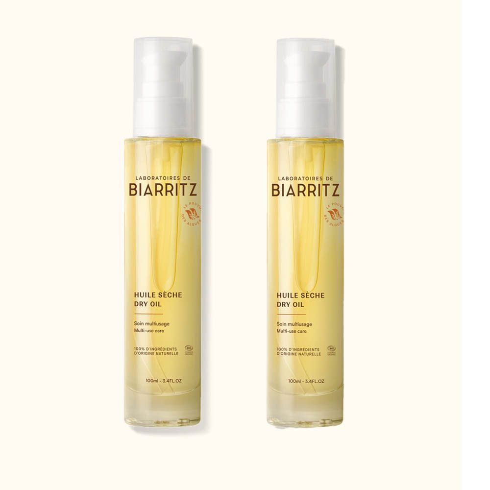 Zwei Flaschen mit weißem Pumpverschluss. Aufschrift: Laboratoires de Biarritz, Huile Sèche Dry Oil. Gelbe Flüssigkeit sichtbar.