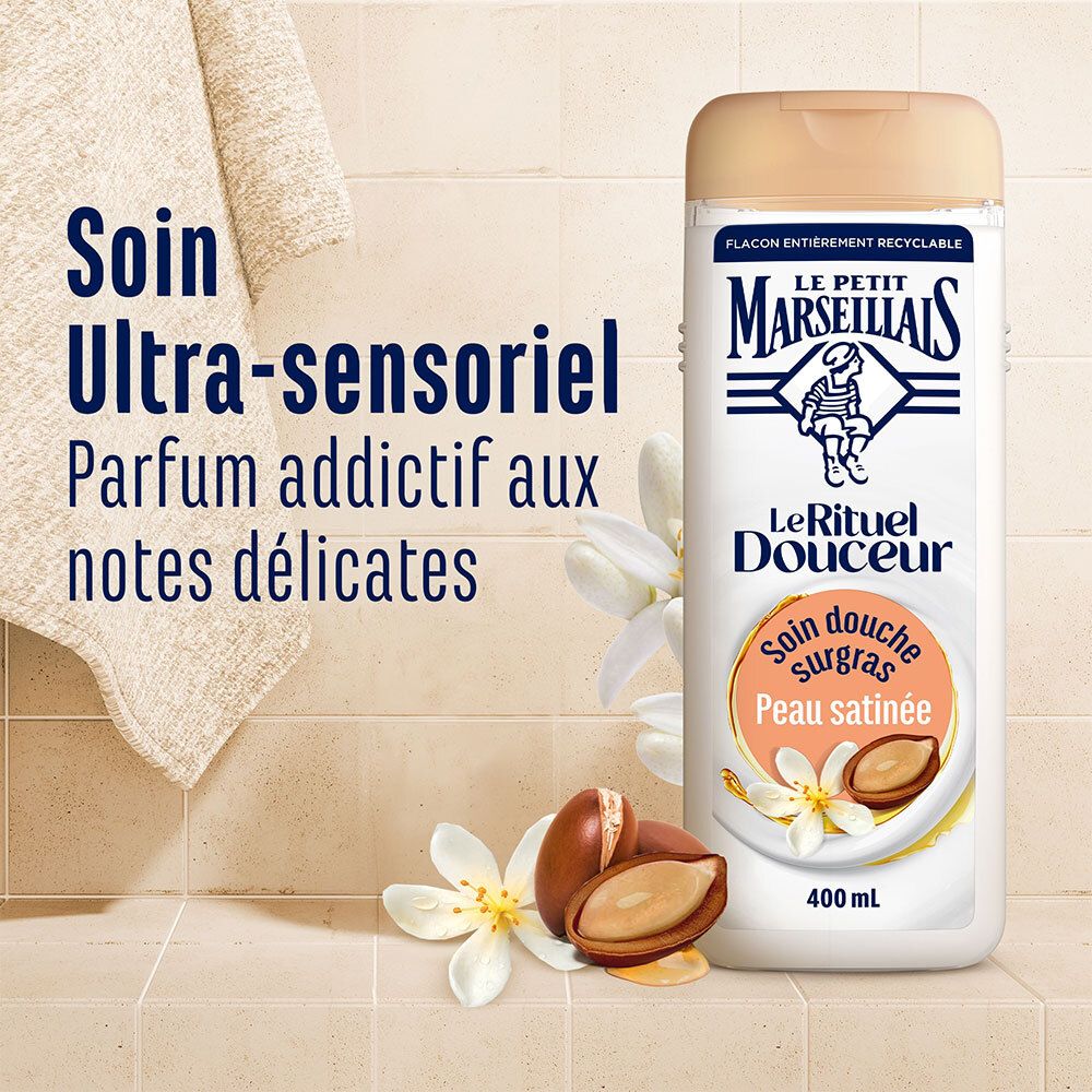 Flacon de produit à côté d'une serviette et de fleurs. Texte: Soin Ultra-sensoriel Parfum addictif aux notes délicates.