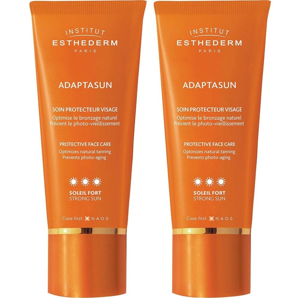 Deux tubes de crème solaire orange. Texte visible: INSTITUT ESTHEDERM, ADAPTASUN, SOIN PROTECTEUR VISAGE, SOLEIL FORT, STRONG SUN.