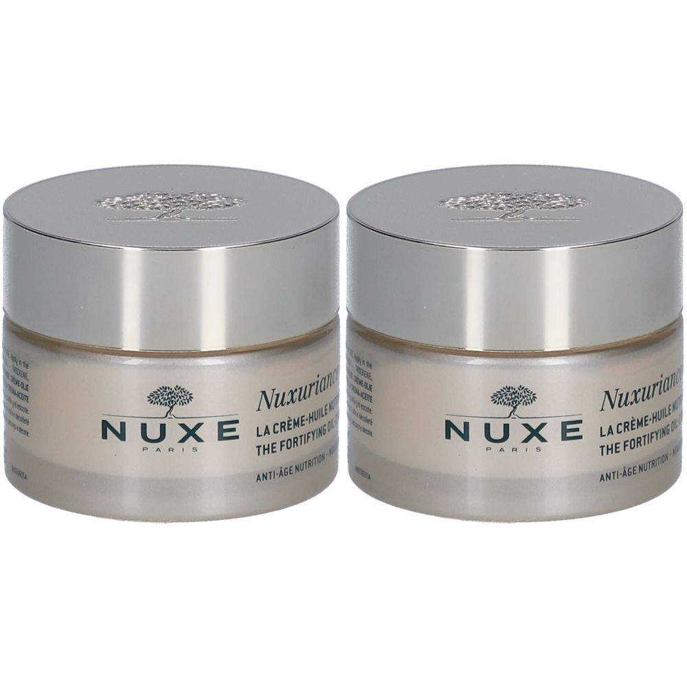 Deux pots de crème-huile nutri-fortifiante Nuxe Nuxuriance® Gold. Pots en verre avec couvercles argentés. Inscription Nuxe Paris.