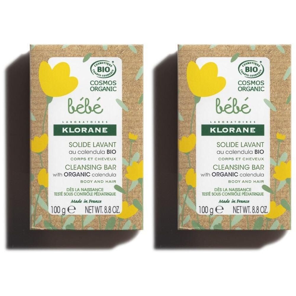 Zwei rechteckige Verpackungen mit Produktinformationen. Aufschrift: KLORANE Bébé, Solide lavant, Cosmos Organic-Zertifizierung.