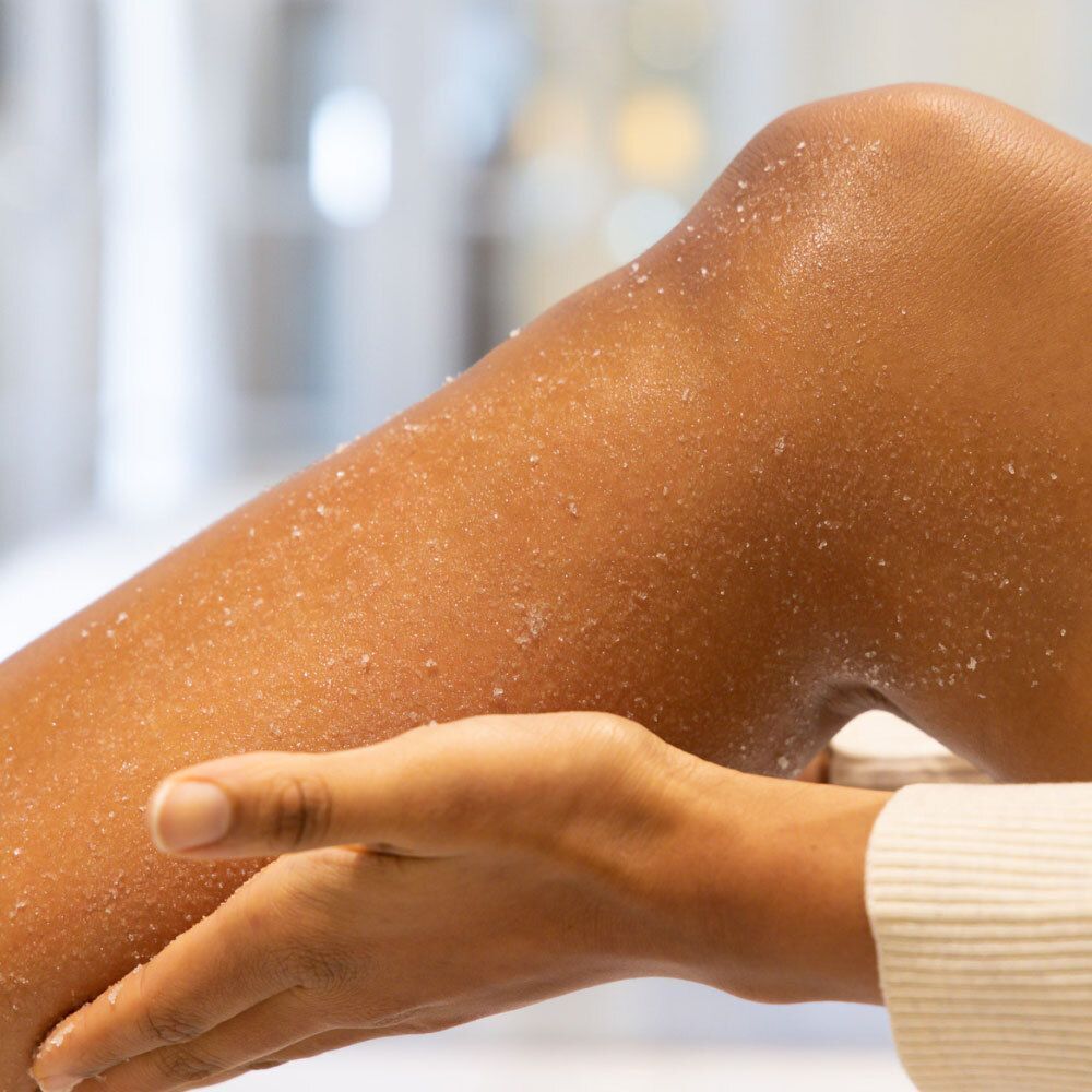 Bein mit Peeling-Salz. Hand berührt Bein. Hautpflegeprodukt.