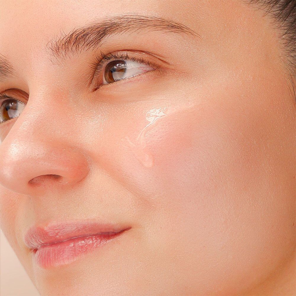 Nahaufnahme eines Gesichts mit einer einzelnen Flüssigkeitströpfchen auf der Haut.