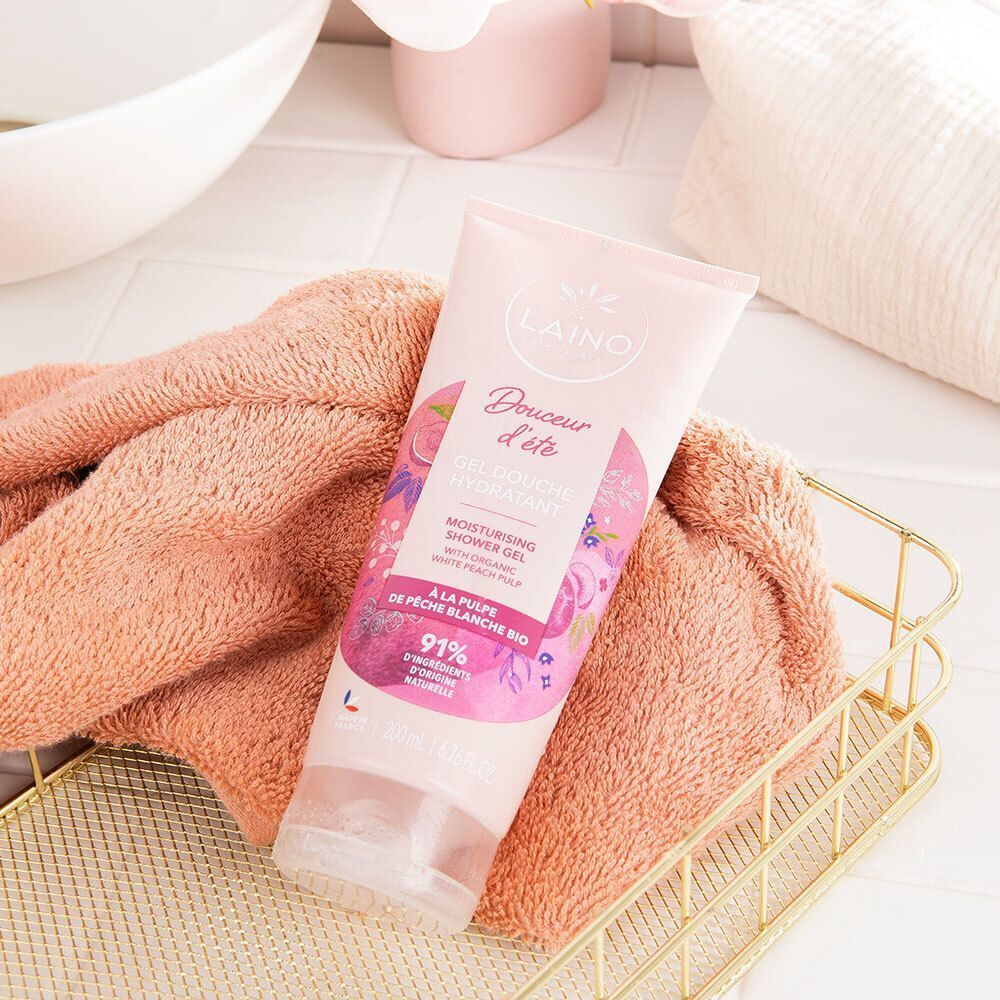 Rosa Tube mit Aufschrift LAINO und floralem Design. Liegt in einem Korb neben einem Handtuch.