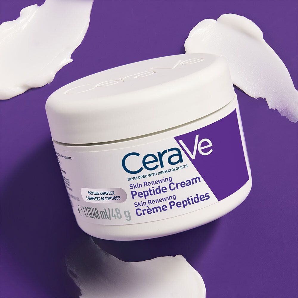 Pot blanc avec accents violets et traces de crème. Inscription : CeraVe Skin Renewing Peptide Cream.