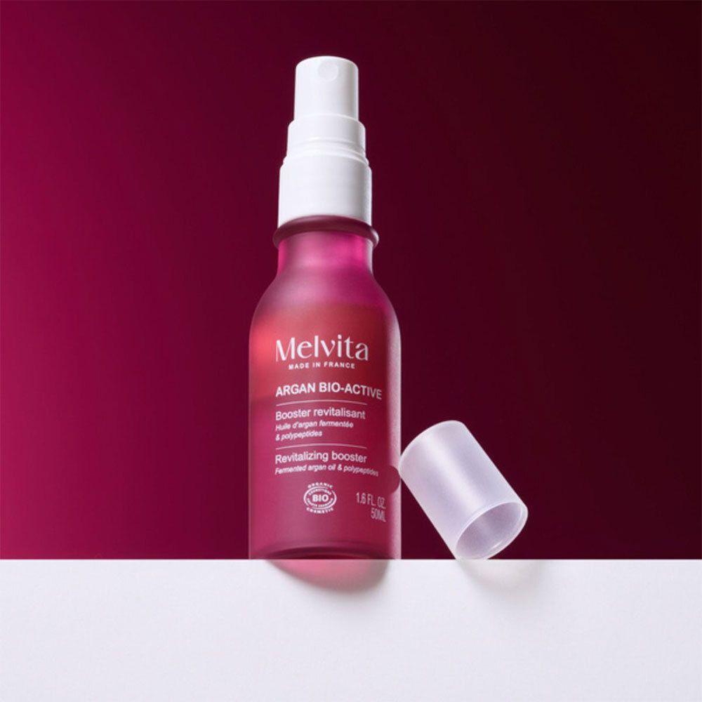 Rote Flasche mit Sprühkopf und separater Kappe. Aufschrift: Melvita Argan Bio-Active.