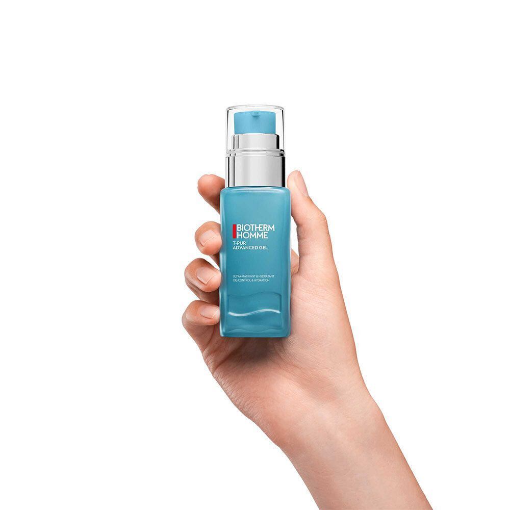 Une main tient un flacon bleu avec une pompe argentée. Le flacon porte l'inscription BIOTHERM HOMME T-PUR ADVANCED GEL.