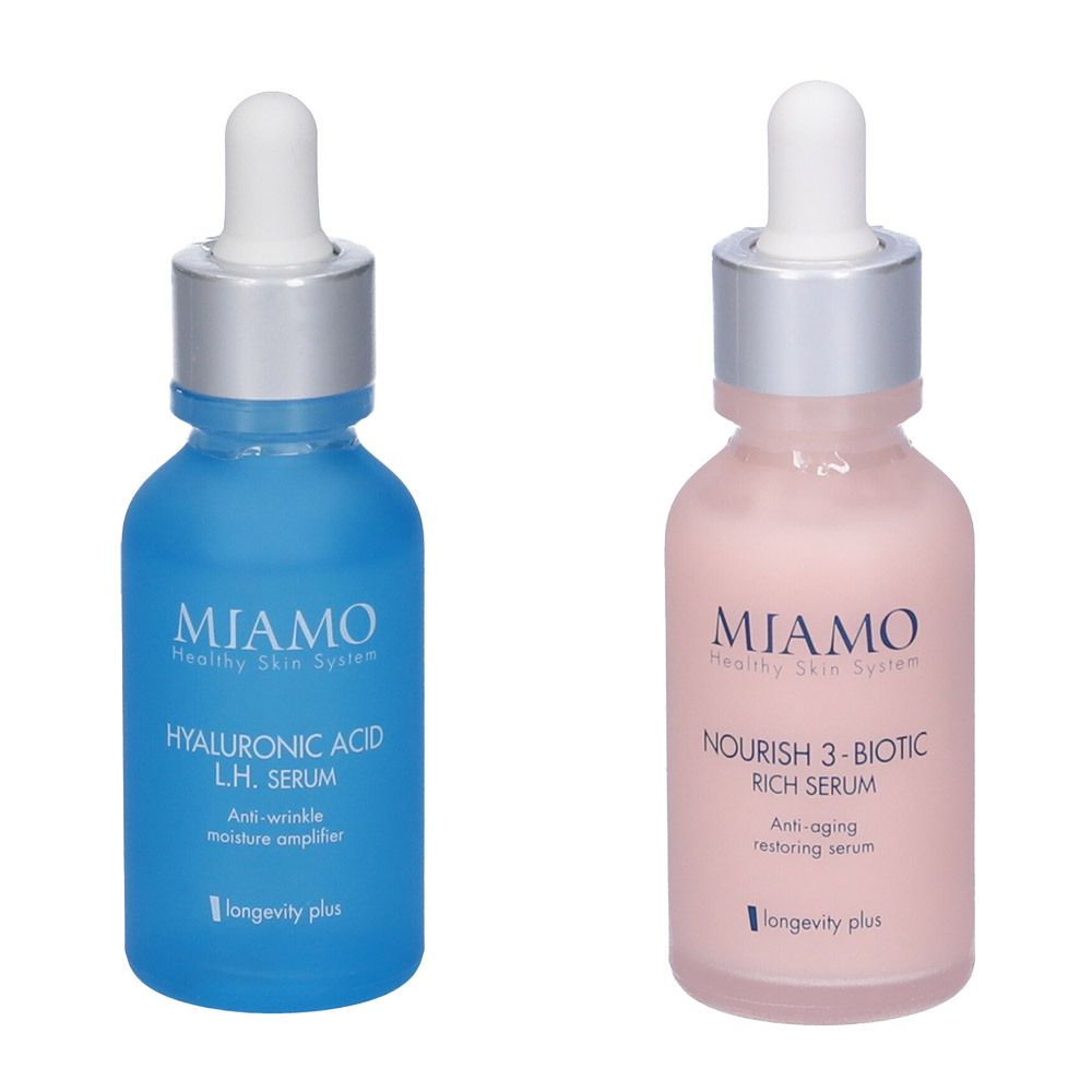 Due flaconi di siero. Blu con "Hyaluronic Acid L.H. Serum". Rosa con "Nourish 3-Biotic Rich Serum". Pipetta e logo "MIAMO".