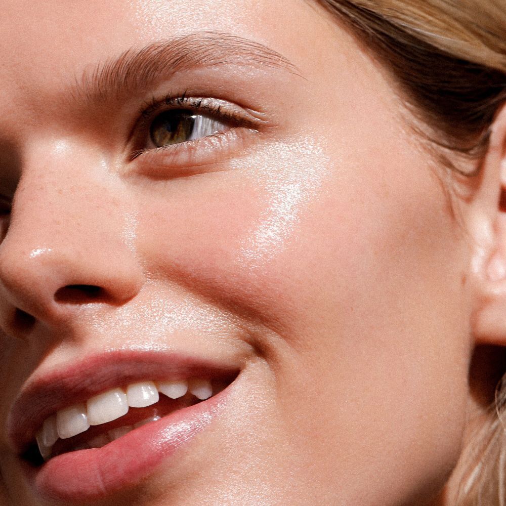 Una donna con pelle radiosa su cui è applicato Dr. Hauschka Illuminating Fluid.