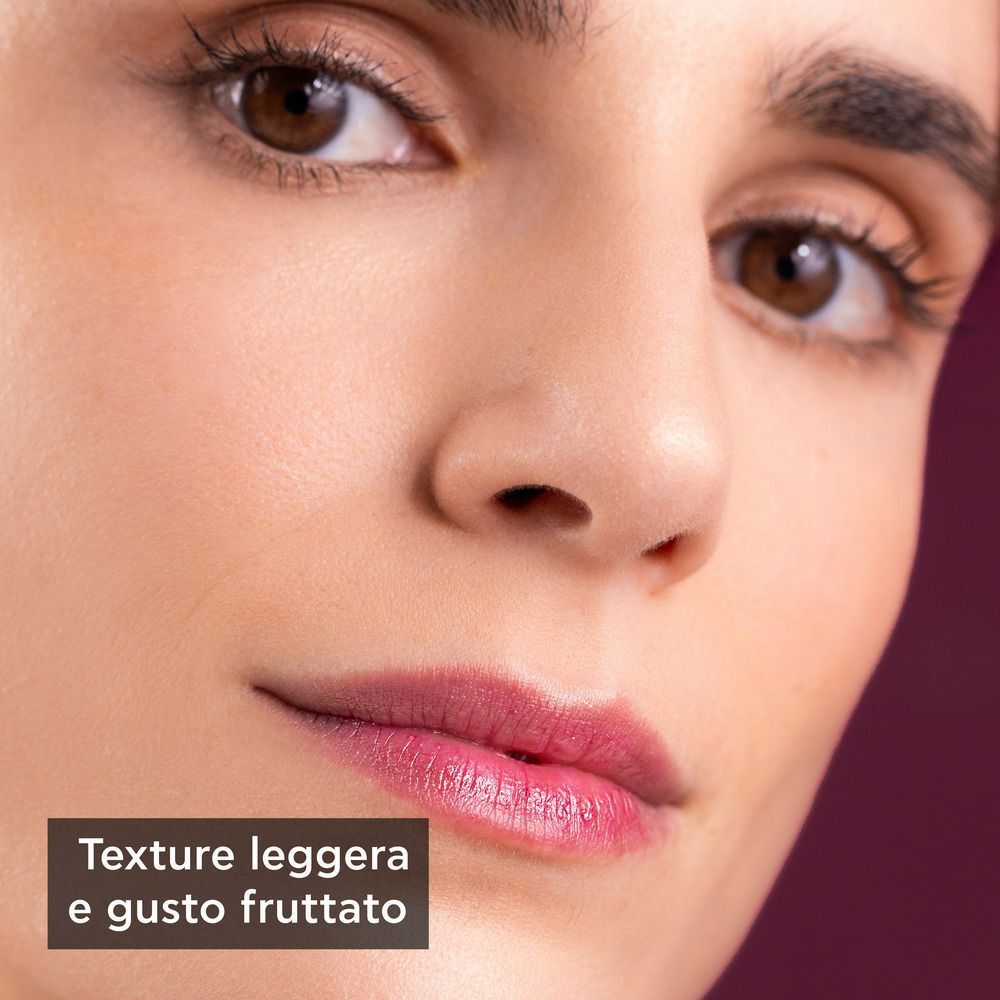 Primo piano di una donna con balsamo labbra dalla texture leggera e fruttata.