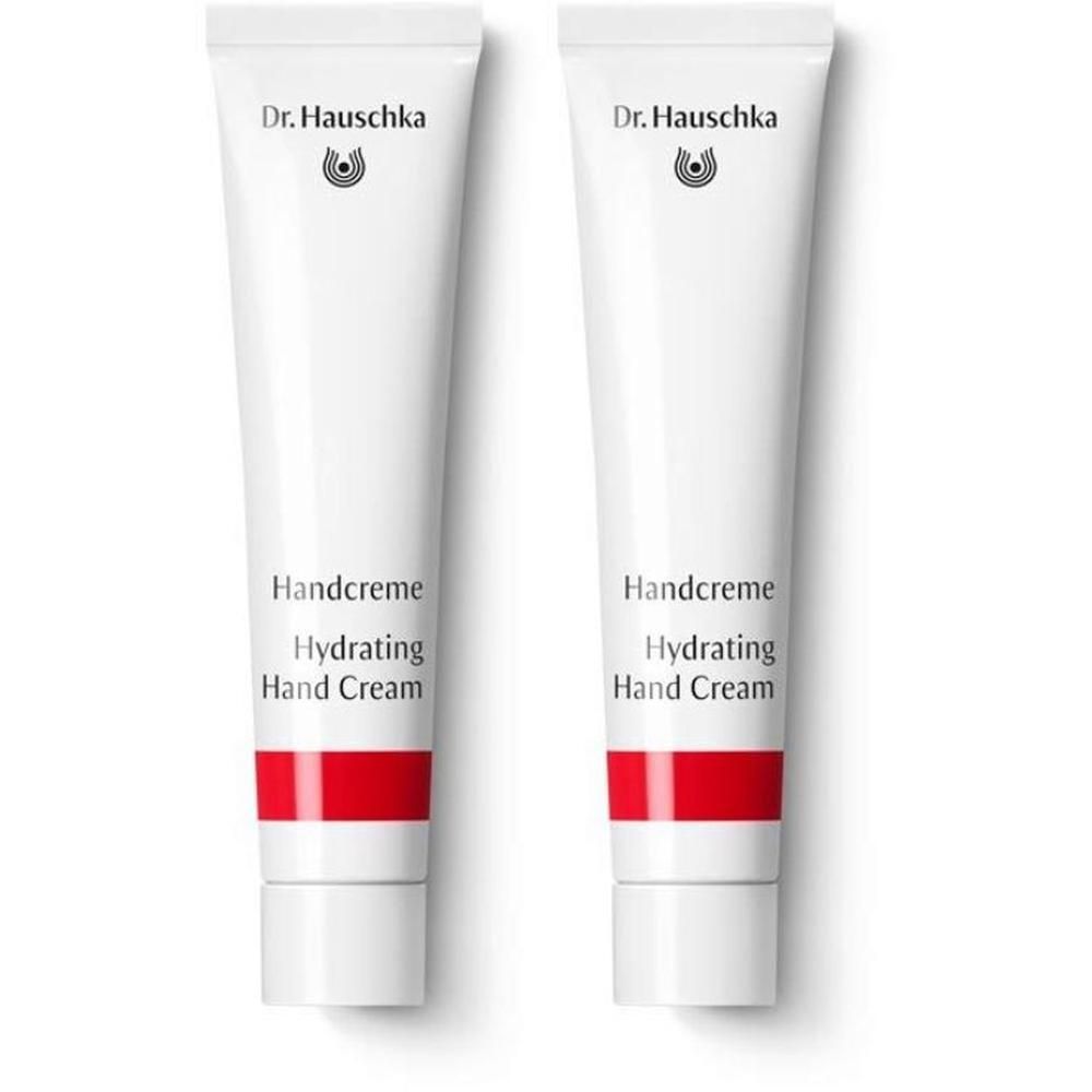 Due tubetti bianchi di crema mani con fascia rossa e logo Dr. Hauschka.