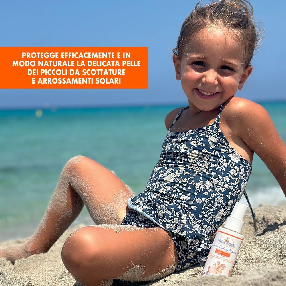 Bambina in spiaggia con latte solare spray SPF50+.