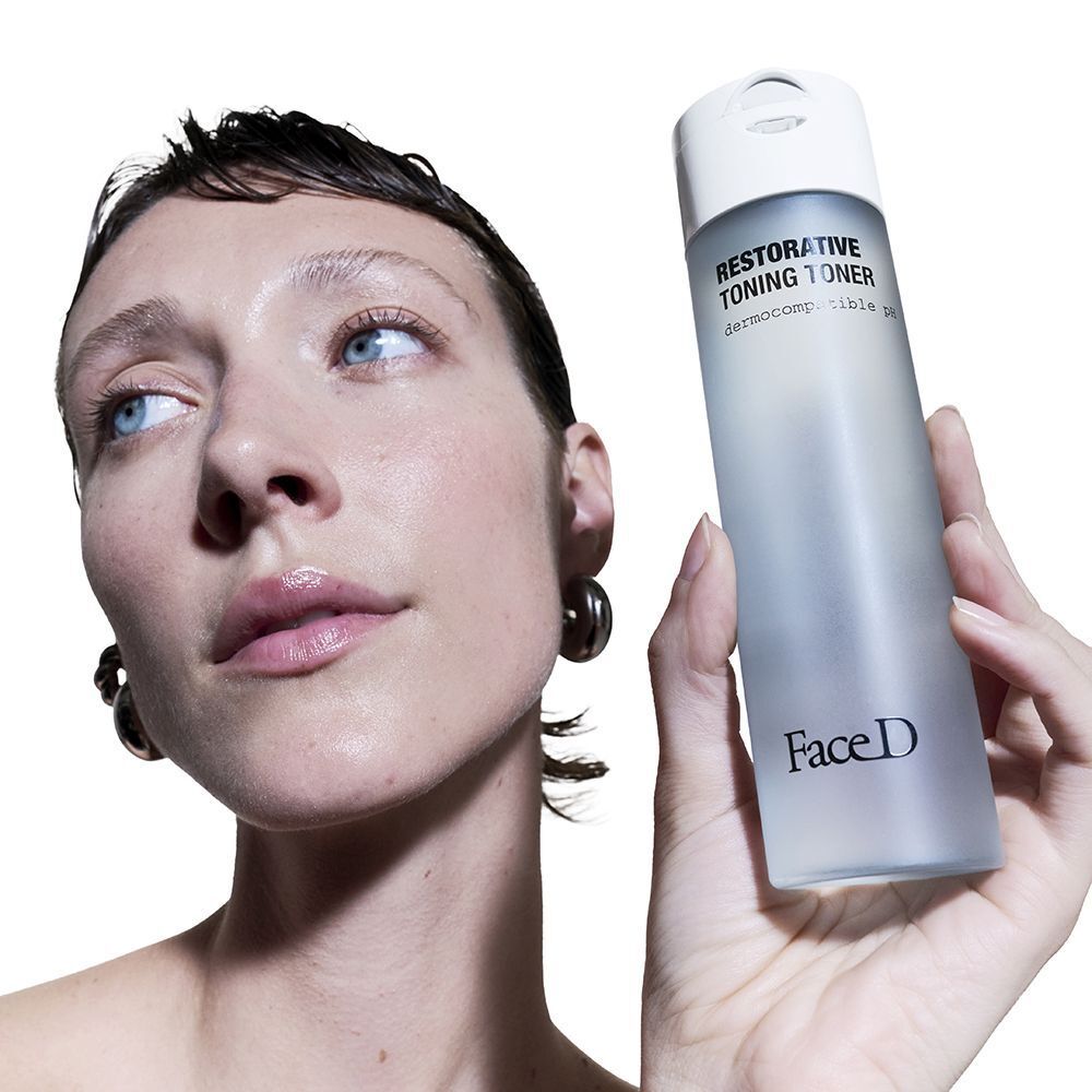 Una donna tiene in mano un flacone di Face D Restorative Toning Toner con pH dermocompatibile.