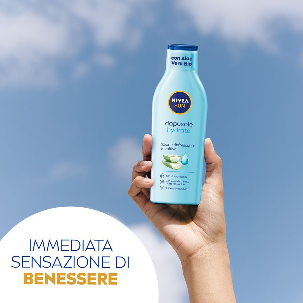 Mano che tiene Nivea Sun Latte Doposole Hydrate sotto un cielo blu.