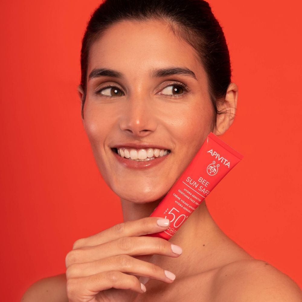 Donna che tiene un tubo rosso di crema viso solare SPF 50+.