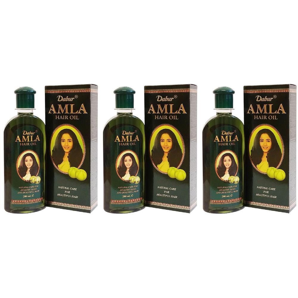 Tre flaconi di olio per capelli Dabur Amla con scatole. Ogni flacone mostra una donna e due frutti.
