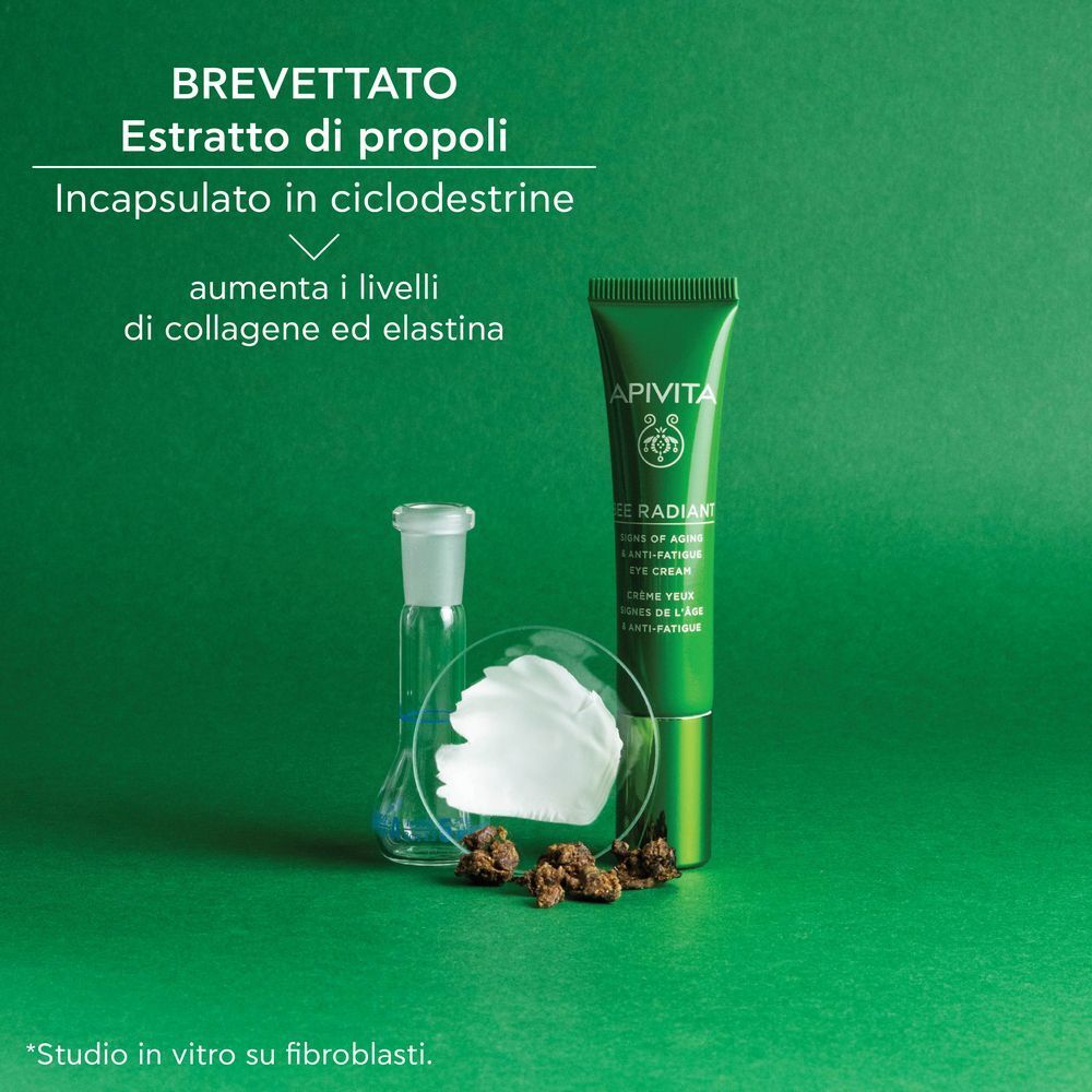 Donna con puntini di crema contorno occhi sotto gli occhi, tiene un tubetto APIVITA Bee Radiant.