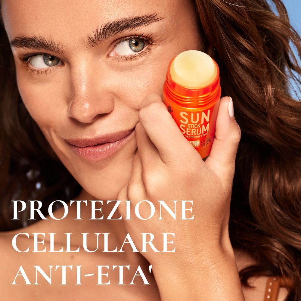 Una donna tiene in mano un Nuxe Sun Stick Siero SPF 50 vicino al viso.
