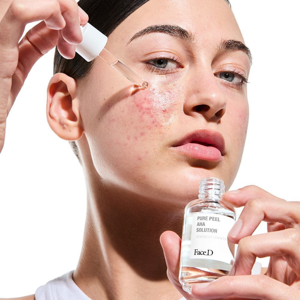 Una donna applica Face D Pure Peel AHA Solution sul viso con un contagocce.