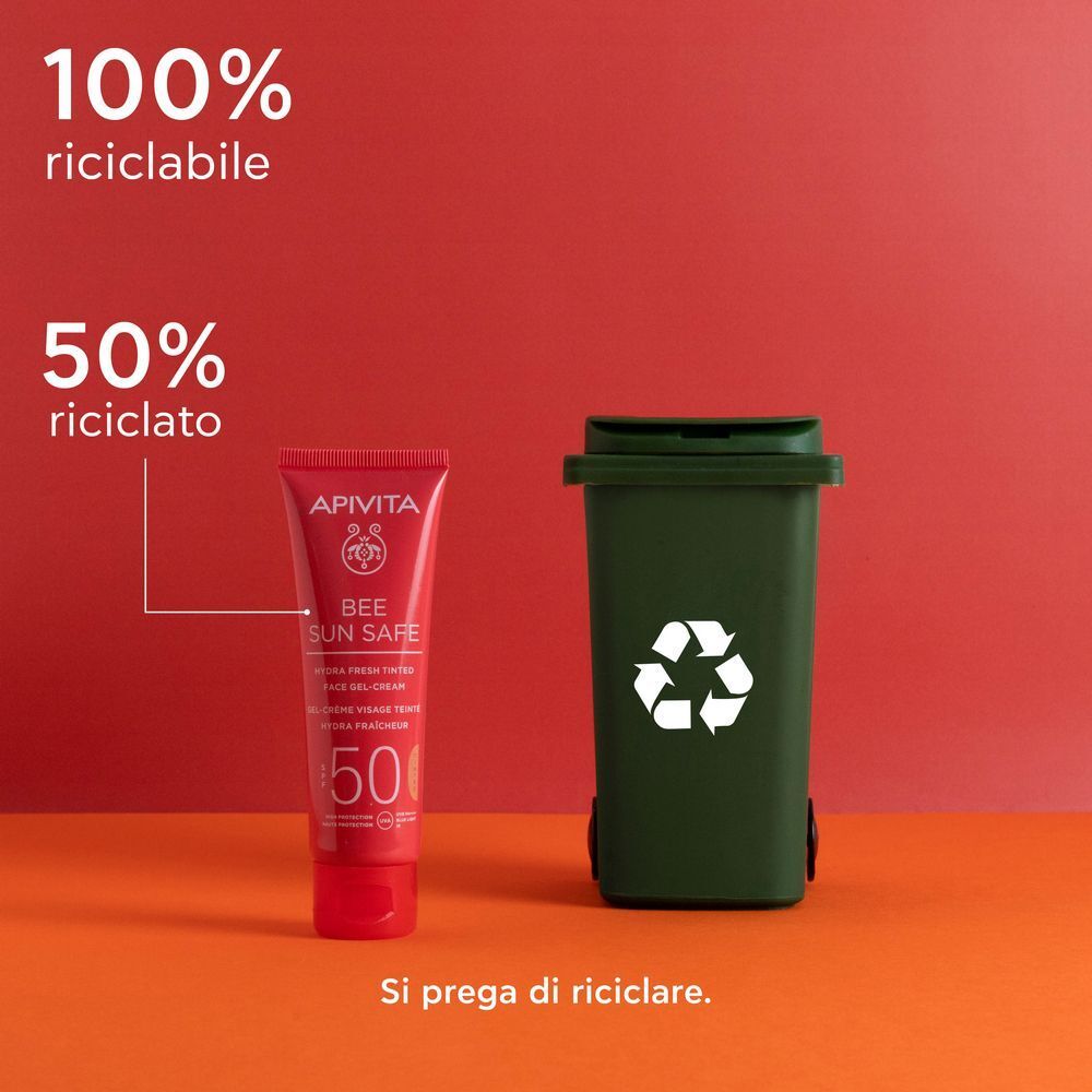 Tubo rosso APIVITA Bee Sun Safe Gel-Crema Colorata SPF50 accanto a un bidone di riciclaggio verde.